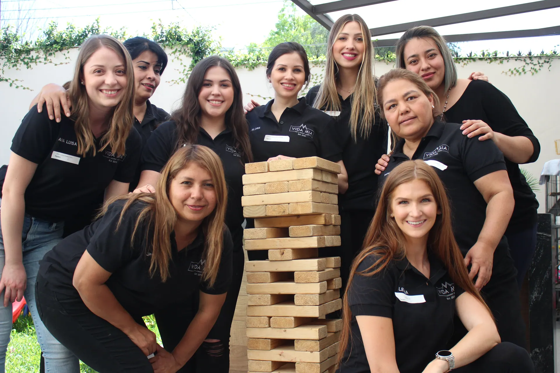 Equipo de jóvenes de ALYAX sonriendo frente a un juego de bloques Jenga, demostrando compañerismo y trabajo en equipo