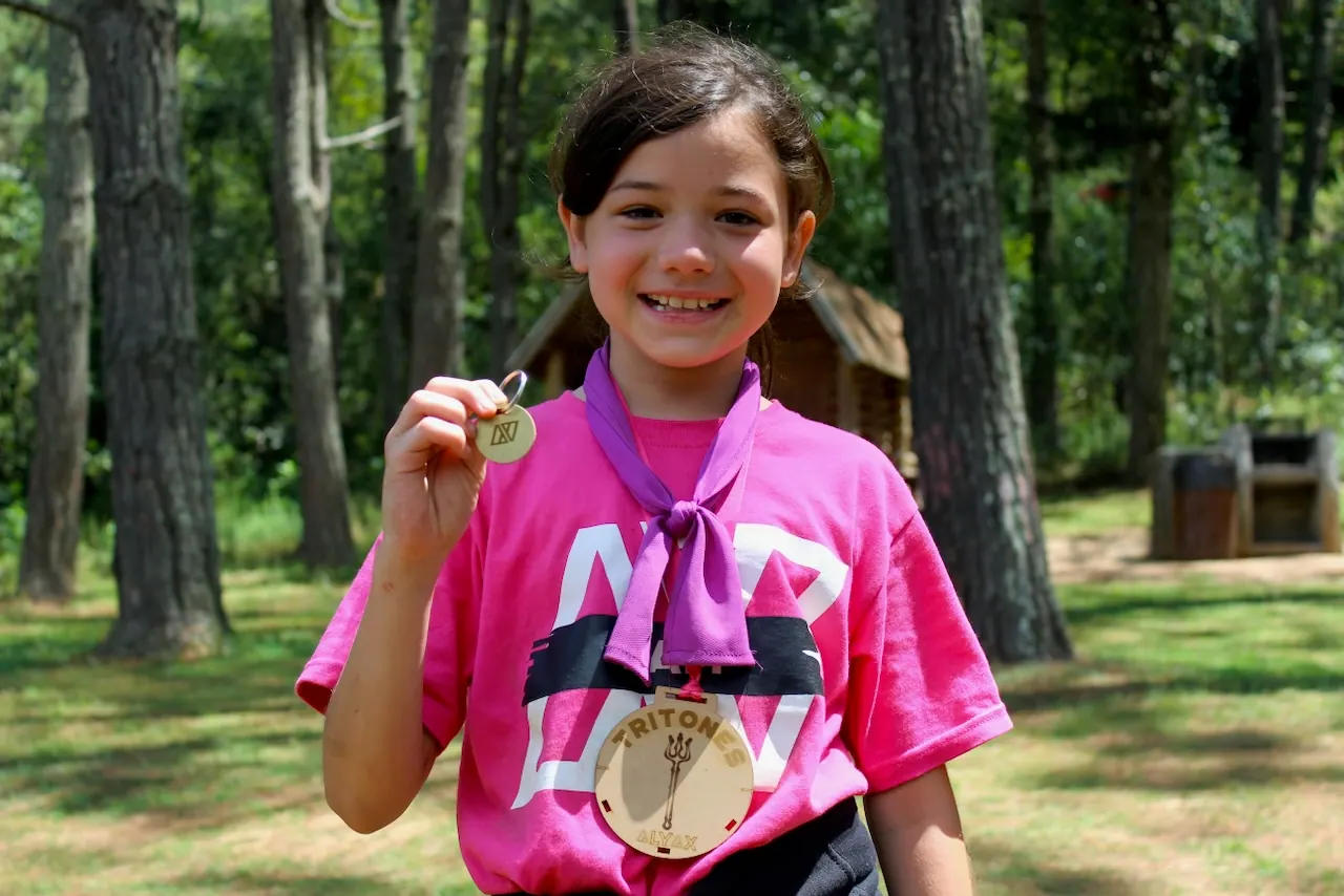 Campista con playera rosa muestra su medalla