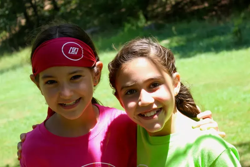 Dos niñas abrazadas sonriendo con bandas en la cabeza