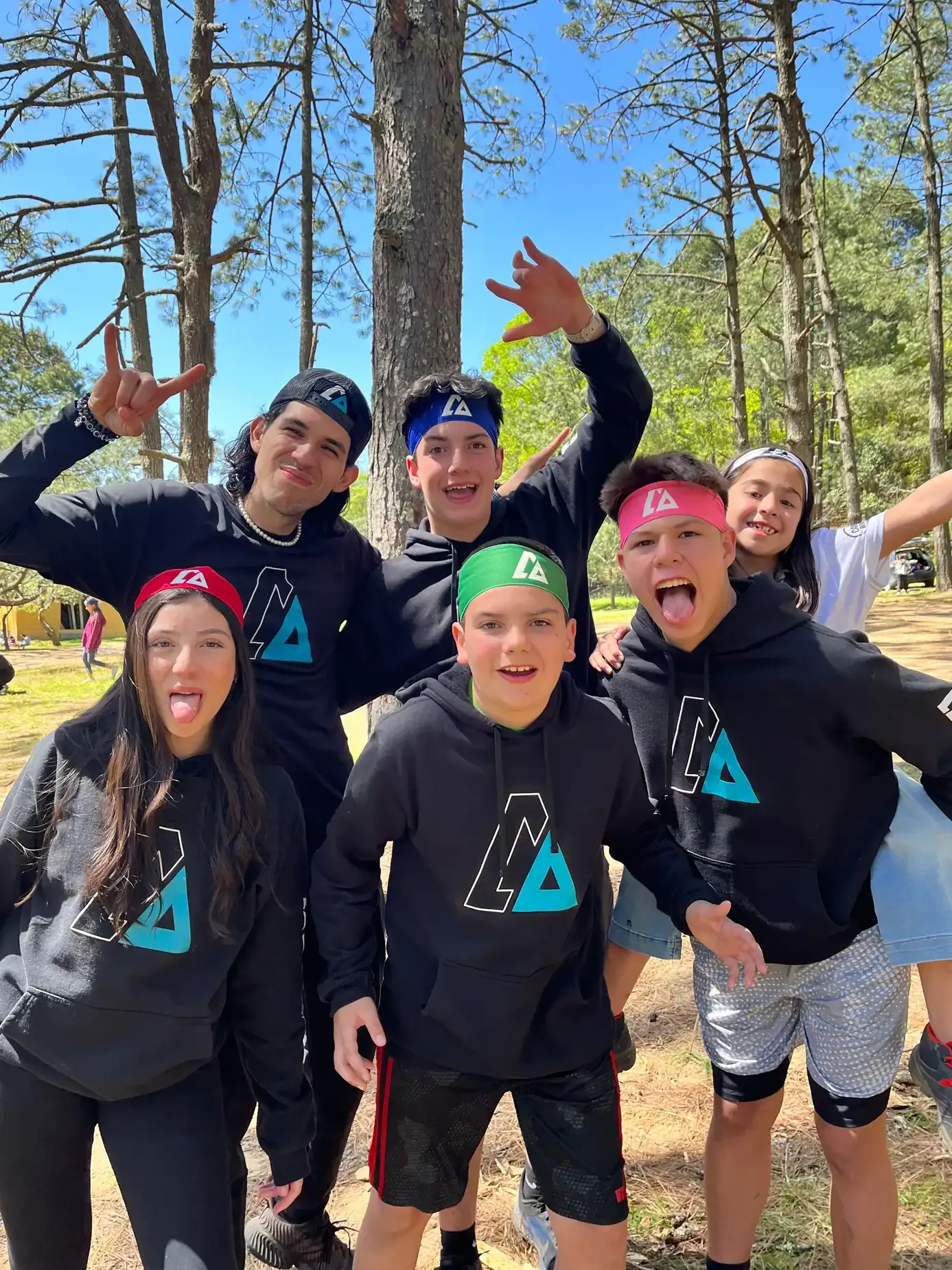Grupo de campistas con sudaderas negras de ALYAX posando divertidos en el bosque