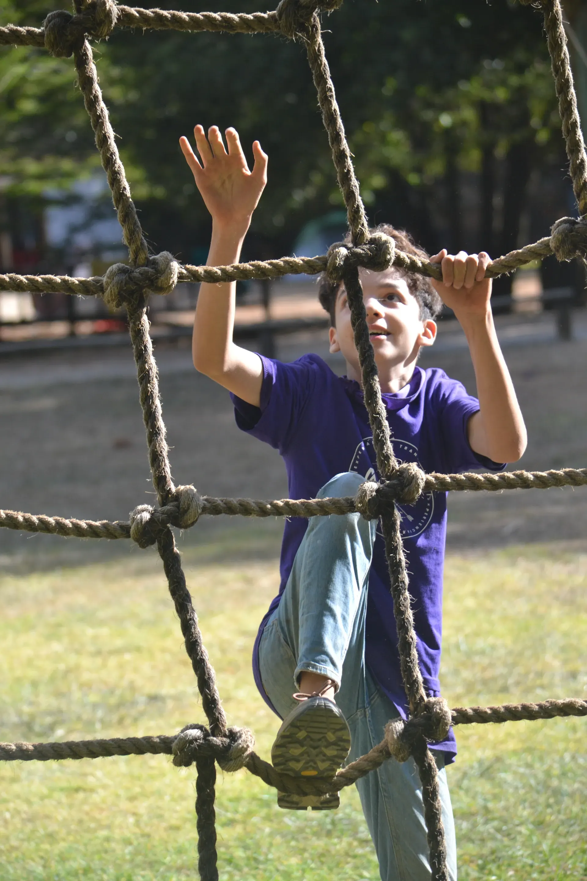 Niño trepando una red de cuerdas, uno de los retos al aire libre del campamento