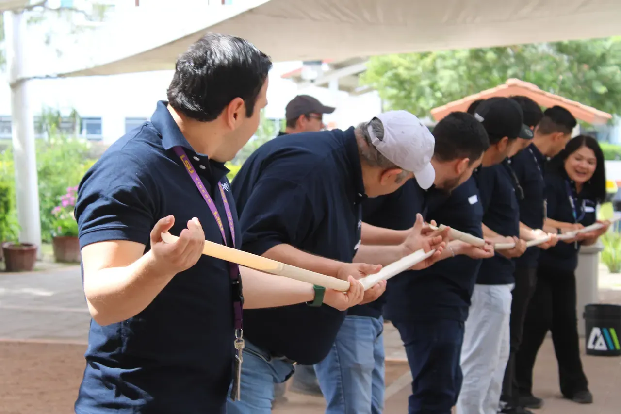 Colaboradores tomados de un palo en una dinámica de coordinación bajo una carpa