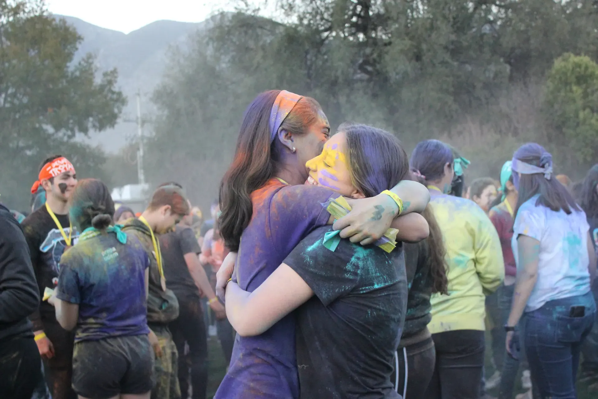 Dos campistas abrazándose después de una actividad con polvos de colores