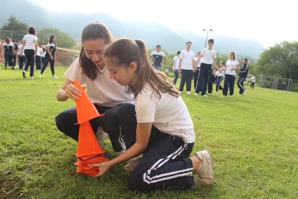 Dos campistas colaborando para acomodar conos durante un juego en equipo