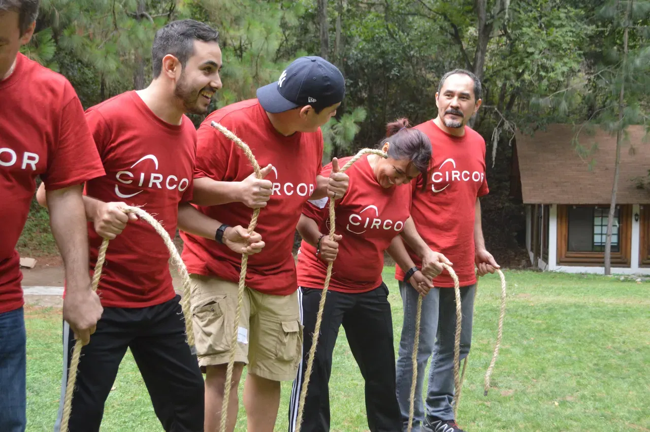 Grupo participando en una dinámica con camisetas rojas, demostrando cómo la unión y la coordinación impulsan el éxito
