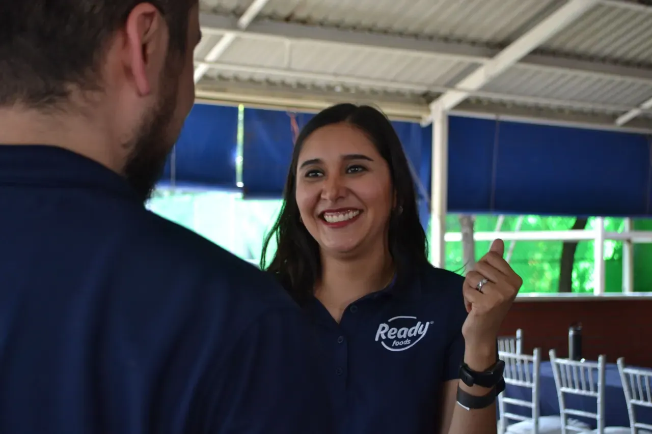 Mujer sonriente en una sesión de trabajo grupal, mostrando entusiasmo por formar parte de un equipo comprometido