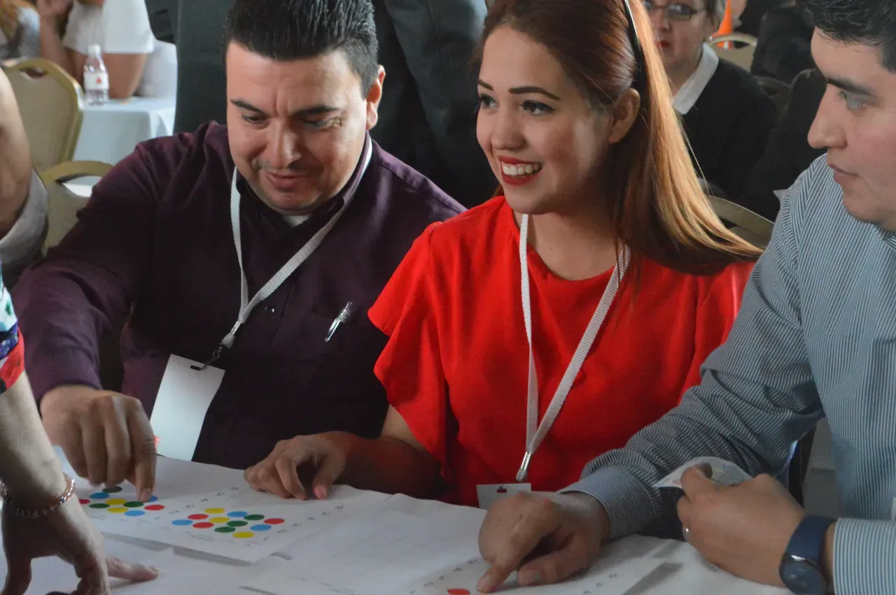 Profesionales interactuando durante una actividad en interiores, compartiendo ideas para alcanzar objetivos comunes