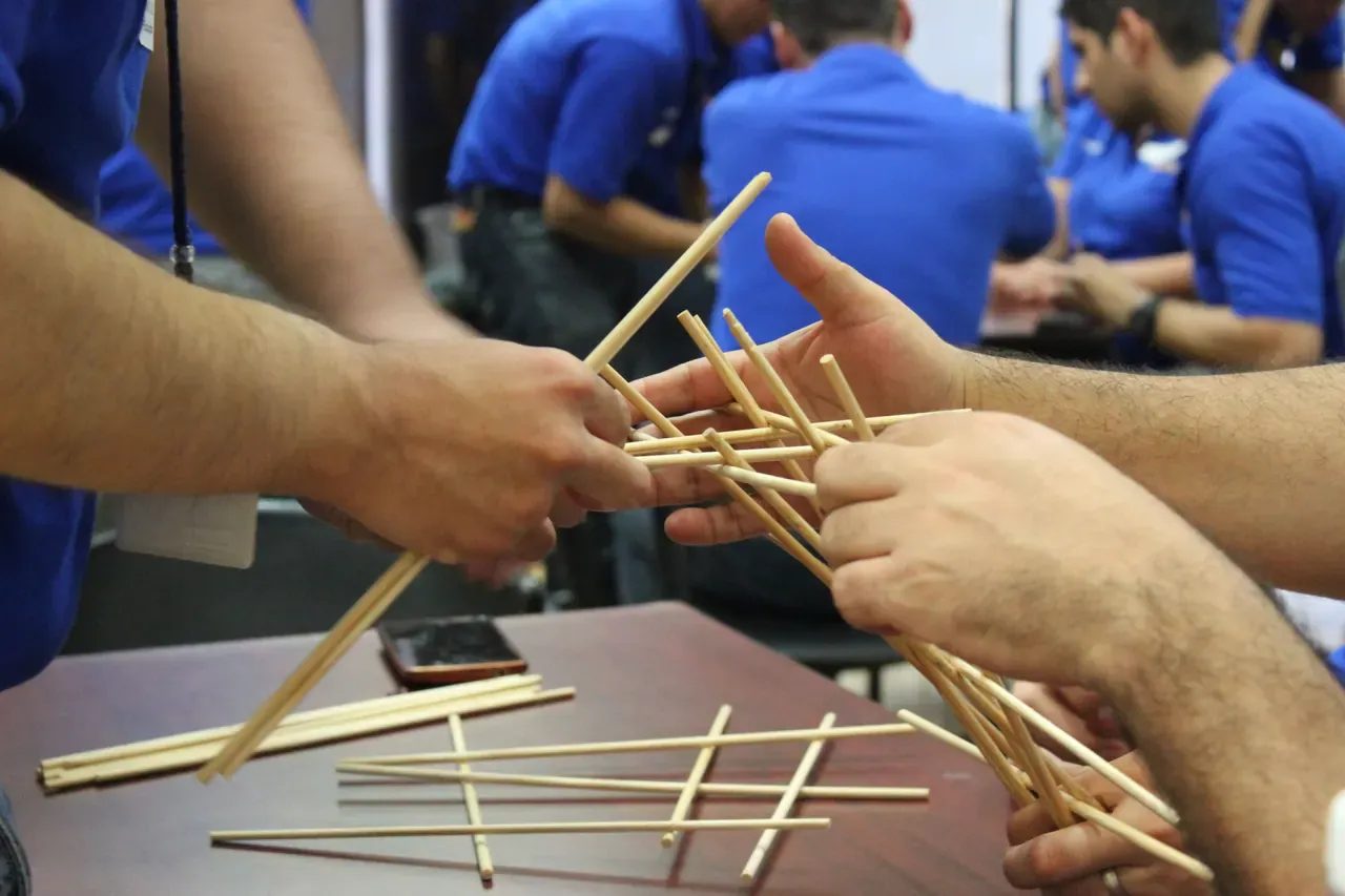 Grupo de personas trabajando en interiores, utilizando recursos simples para resolver un desafío en equipo