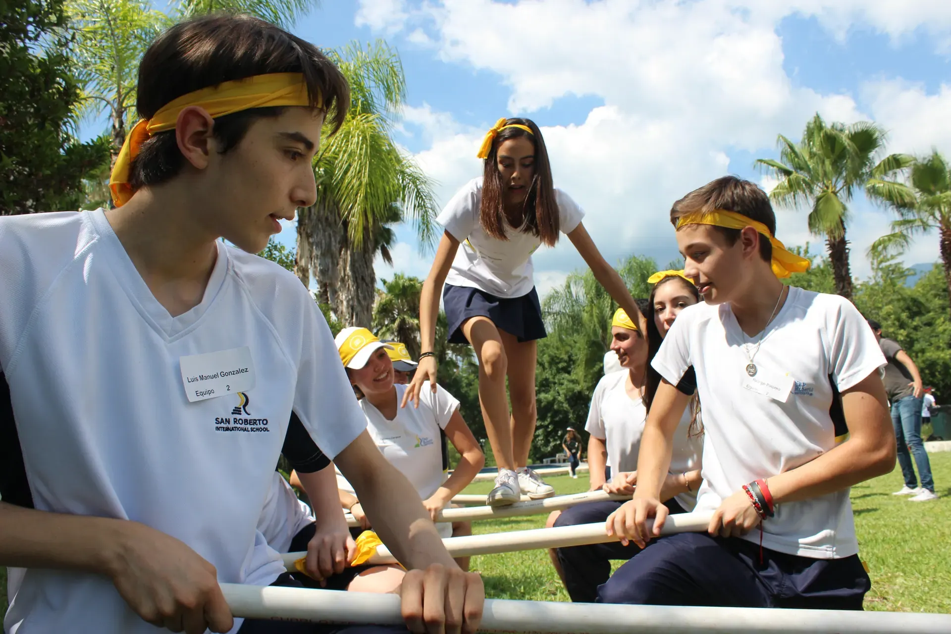 Estudiantes colaborando en una dinámica al aire libre, trabajando juntos para fortalecer la integración y el trabajo en equipo