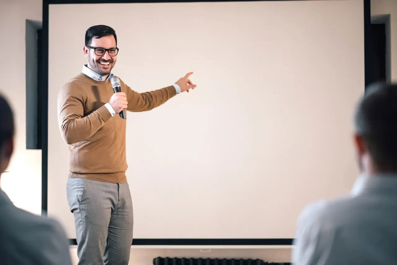 Ponente señalando a la audiencia, destacando un momento clave de aprendizaje en una plática motivacional organizada por ALYAX