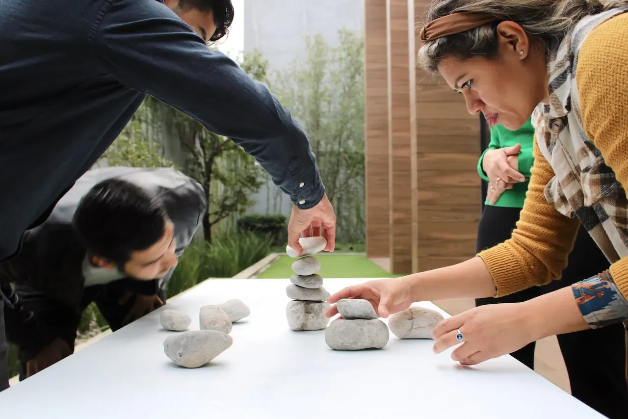 Mano apilando piedras en un ejercicio simbólico, representando el equilibrio necesario para liderar de forma efectiva