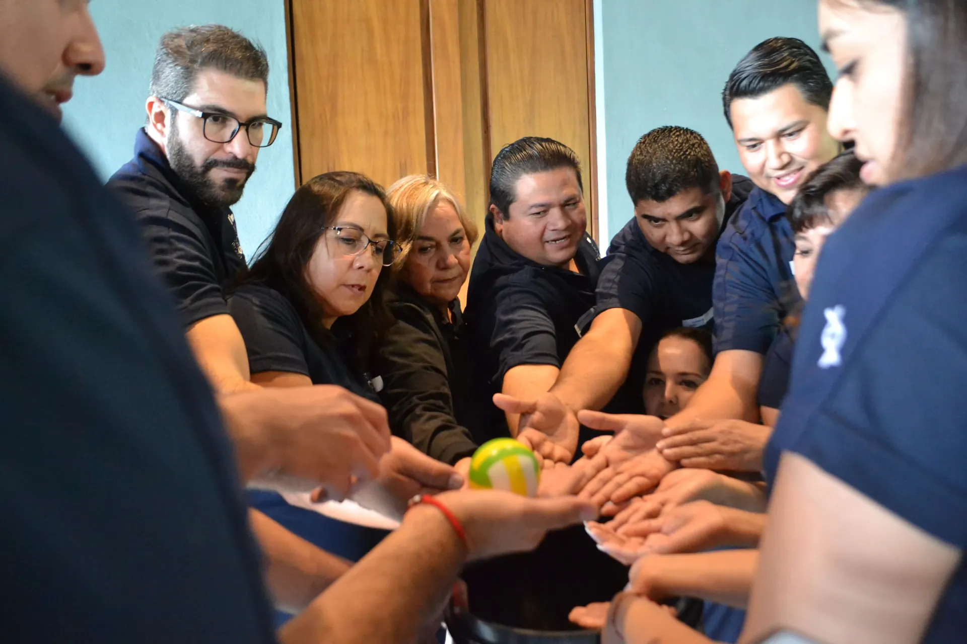 Compañeros de trabajo juntando las manos al centro del círculo en una dinámica de integración